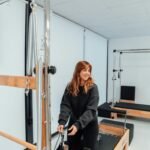 a woman standing in a gym holding a bar